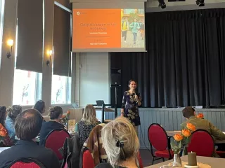 Een groep mensen zittend aan tafel kijkend naar een presentatie